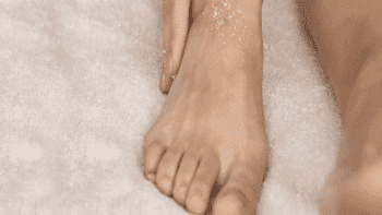 Talco nos pés: imagem mostra mulher hidratando seus pés.