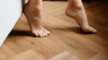 Tratar a frieira: pés femininos pisando no chão de madeira.