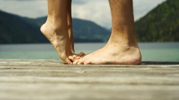 Cuidados com os pés: mulher na ponta do pé ao lado de homem em um píer ao ar livre.
