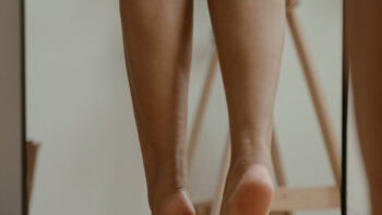 Rachaduras nos pés: mulher descalça, na ponta dos pés, de costas.